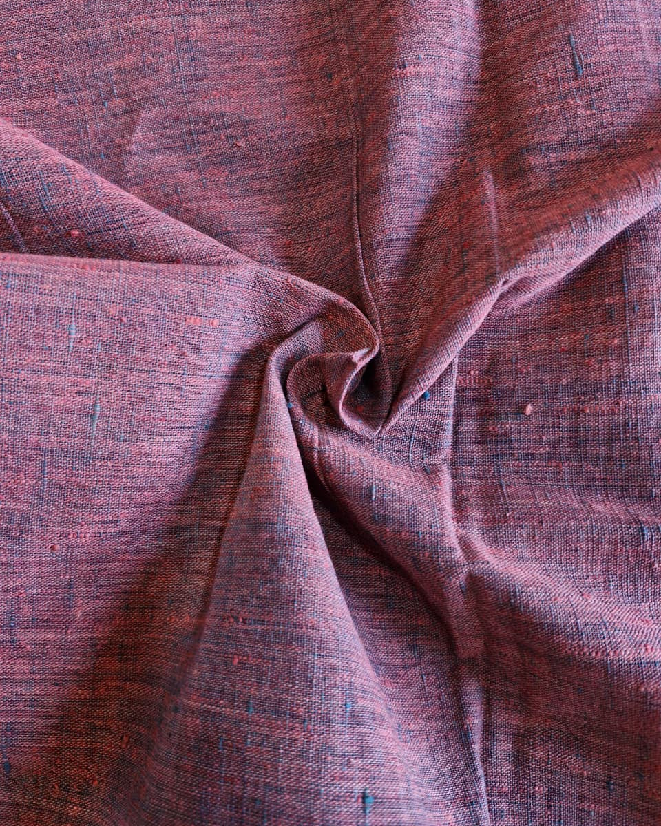 A close-up of draped woven fabric with a heathered texture in muted mauve, burgundy, and brown tones, showing the material's weave and folds.