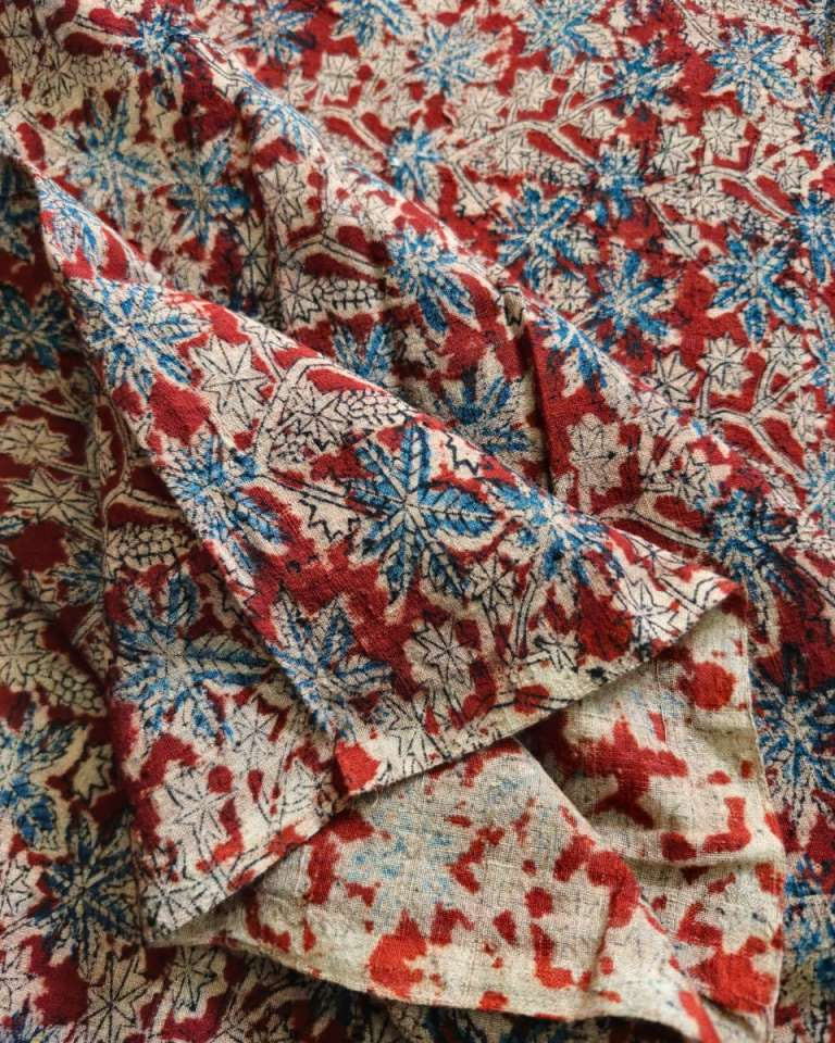 Close-up of patterned fabric with red, blue, and beige colors.