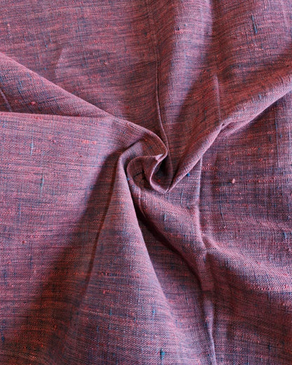 A close-up of draped woven fabric with a heathered texture in muted mauve, burgundy, and brown tones, showing the material's weave and folds.