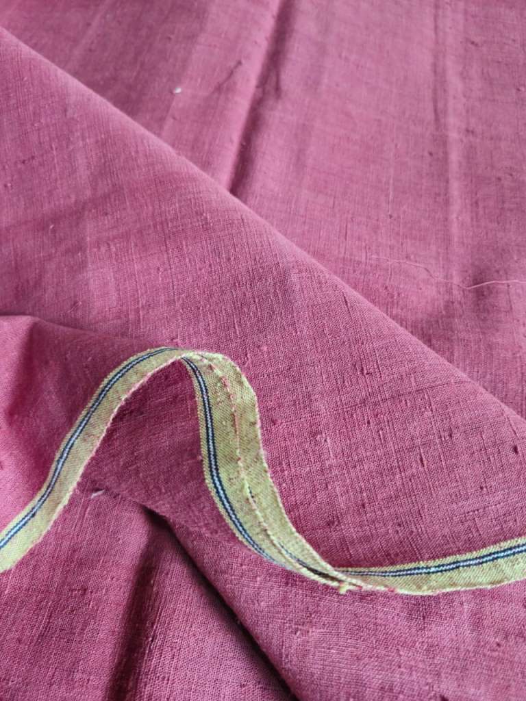 Close-up of pink fabric with a decorative green and blue border