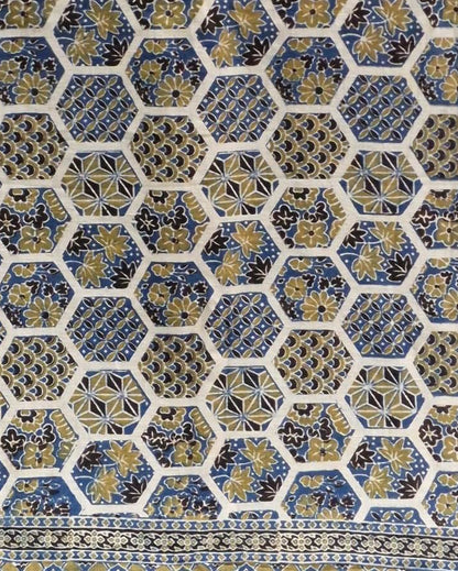 A close-up of a patterned textile or fabric with a repeating hexagonal motif in blue, gold, black, and off-white, plus a decorative border along the right edge.