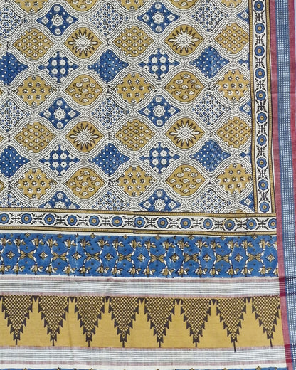 A close-up of a patterned textile or fabric panel with repeating geometric motifs in blue, mustard yellow, white, and black, plus decorative border bands.