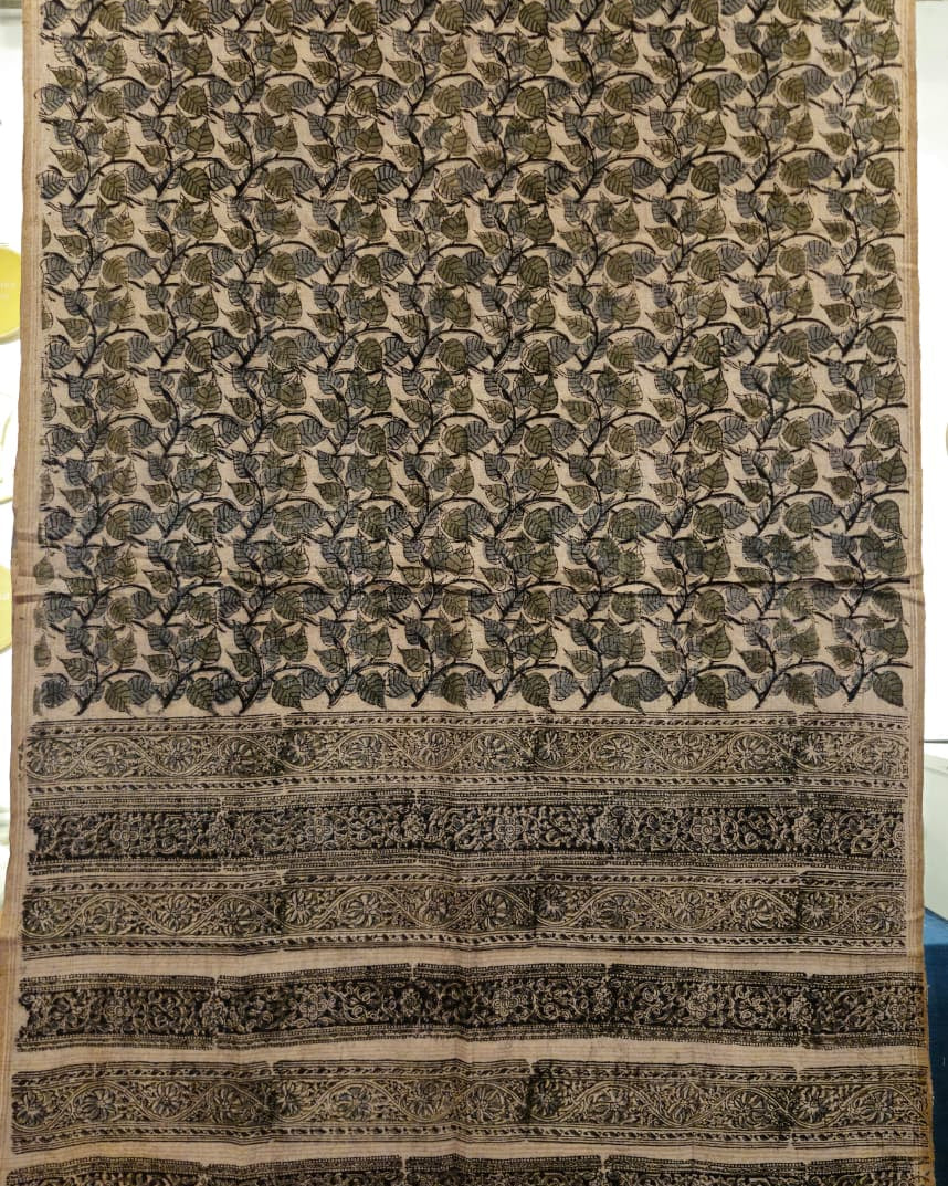 A rectangular handloom fabric or sari with an intricate floral block print pattern in olive green and black on a beige background, featuring a wide decorative border at the bottom.