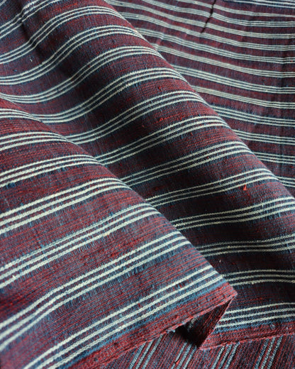 A close-up of striped fabric with horizontal bands in dark red, navy, and off-white, showing a textured woven material with soft folds.