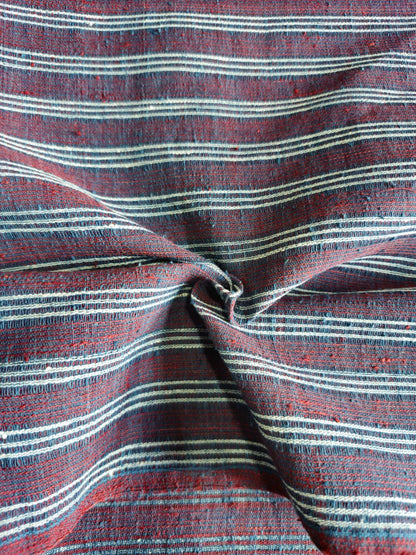 A close-up of a striped woven fabric with horizontal lines in red, navy, and off-white, gathered in the center to show texture and pattern.