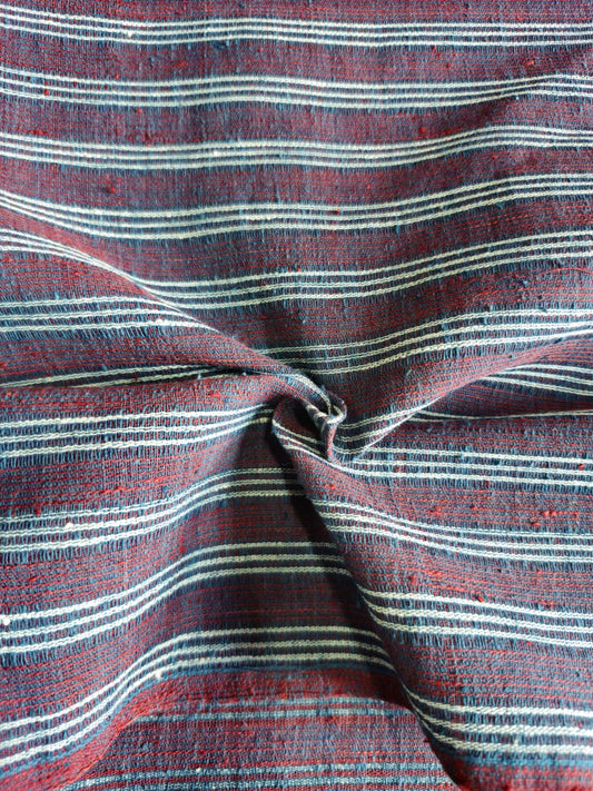 A close-up of a striped woven fabric with horizontal lines in red, navy, and off-white, gathered in the center to show texture and pattern.