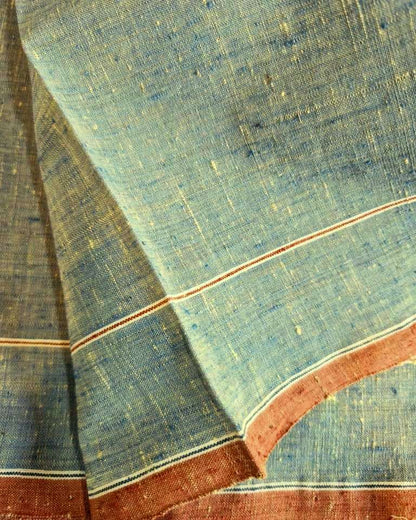 A close-up of a textured blue fabric with fine slub yarns, featuring a rust-red border with thin cream stripes.
