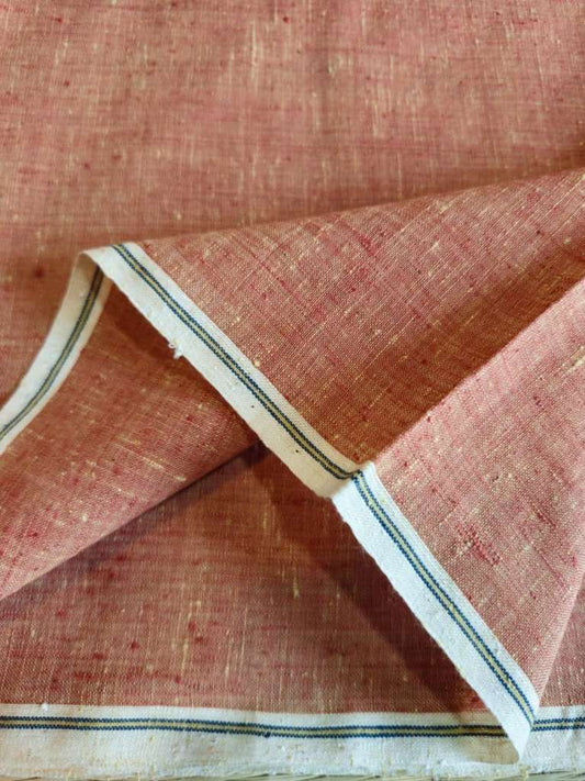 A close-up of a folded piece of textured linen fabric in a dusty rose pink color, showing its woven texture and a white border with thin blue stripes.