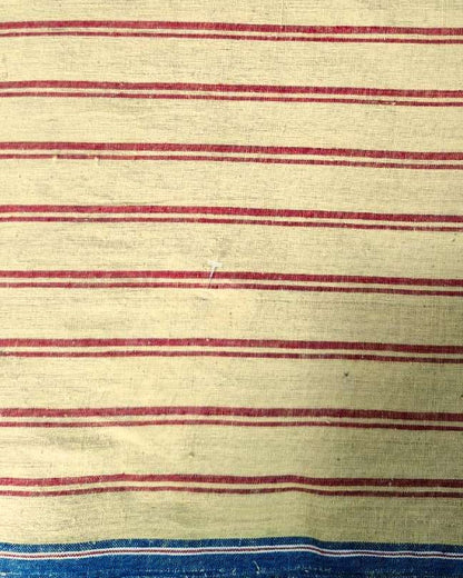 A close-up of a striped textile, likely a vintage striped blanket or towel, featuring horizontal red stripes on a cream-colored background, with a blue and white striped border at the bottom.