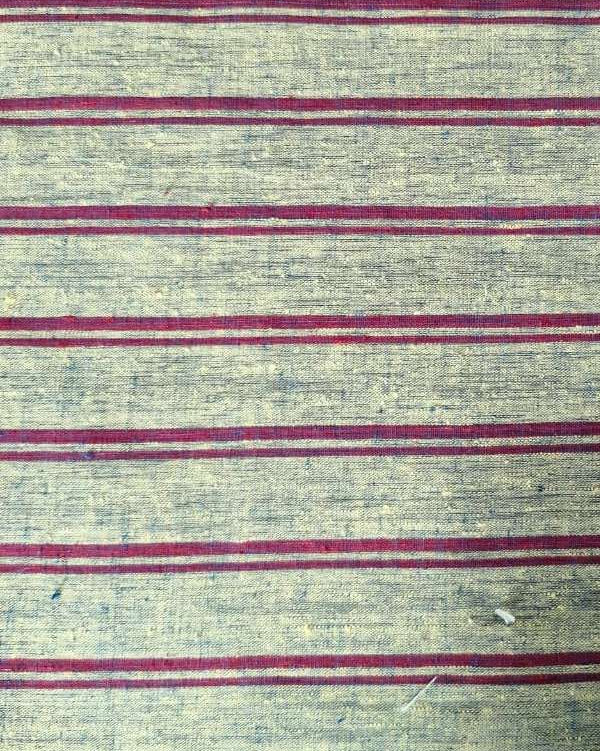 A close-up of a woven textile with a textured beige base and horizontal stripes in muted red and gray.