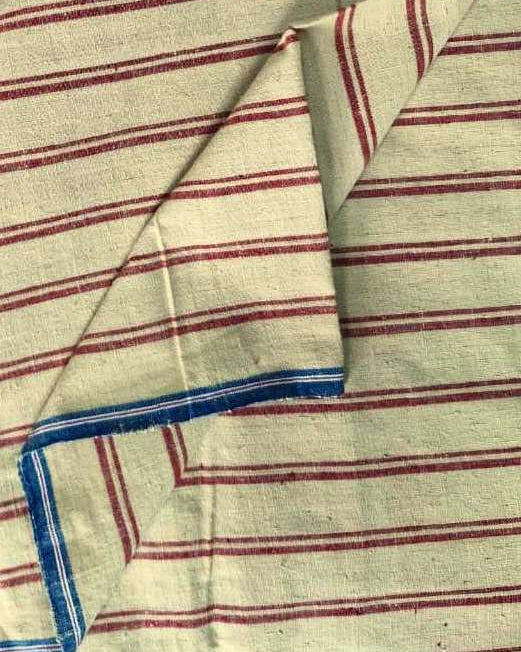 A close-up of a striped textile, likely a cotton napkin or table linen, featuring a cream base with thin red stripes and a blue striped border.