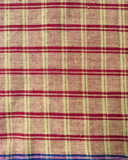 A close-up of a woven fabric with a plaid pattern, featuring a beige base with red horizontal stripes and vertical stripes in cream and dark blue.