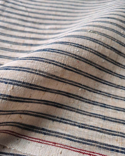 Close-up of a woven fabric with horizontal navy blue and red stripes on a warm beige background.