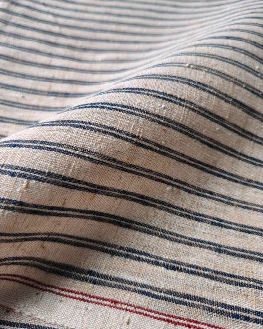Close-up of a woven fabric with horizontal navy blue and red stripes on a warm beige background.